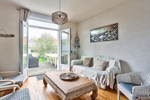 Un salon chaleureux avec une table basse en bois, un canapé blanc et des fauteuils en osier.