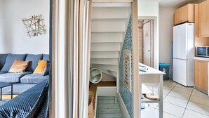 A modern apartment with a staircase leading to a balcony, a kitchen with a refrigerator and microwave, and a living area with a sofa and cushions. - Superb house for 6 people - close to the beach (Dinard)