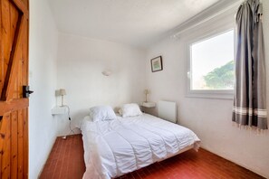 Une chambre à coucher avec un lit, une fenêtre, une lampe et une porte en bois.
