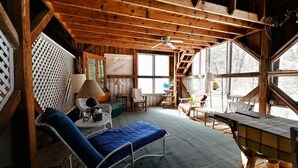 L’intérieur d’un chalet rustique comprend un lit en mezzanine, une table à manger et un ventilateur de plafond.