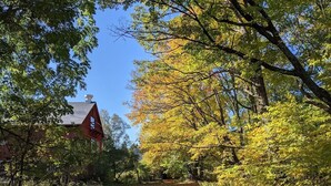 Une construction rouge, ressemblant à une grange, entourée d’arbres aux feuilles d’automne.