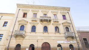 A historic building with a symmetrical facade, multiple windows, and ornate balconies.