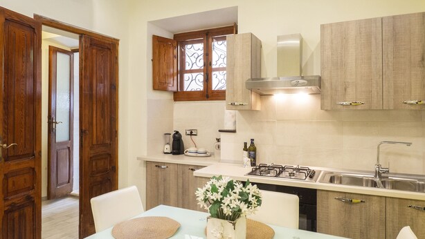 A kitchen with wooden cabinets, a gas stove, a sink, and a window with decorative ironwork.