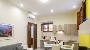 A compact living space with a dining area, kitchen, and a painting on the wall.
