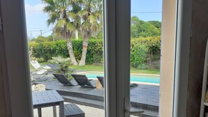A view of a pool area with lounge chairs and a table, surrounded by greenery and palm trees. - Villa Les Palmiers, 15 minutes from Monaco, Nice and the seaside. (Èze)