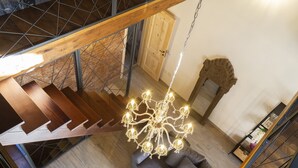 Een trap met houten treden en metalen leuningen, een kroonluchter en een deur in een kamer met een houten vloer.