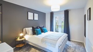 Un dormitorio con cama, mesita de noche y vistas al exterior.