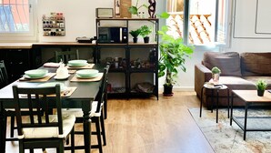 Ein Essbereich mit einem Holztisch, Stühlen und einem schwarzen Metallregal mit Küchengeräten und Dekoration.