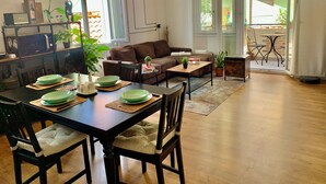 Ein modernes Wohnzimmer mit Essbereich, einem braunen Sofa und einem Holztisch mit grünen Tellern.