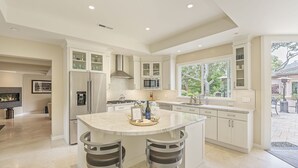 A modern kitchen with a large island, stainless steel appliances, and ample natural light from large windows. - 3885 Pebble Beach Oasis - Indoor / Outdoor Living (Pebble Beach)