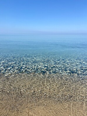 Ein klarer Blick auf einen Kiesstrand mit flachem Wasser.