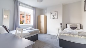 A modern bedroom with two beds, a desk, and a wardrobe. - Lily Apartment 1- 2bed in Bedlington (Bedlington)