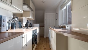 A modern kitchen with wooden countertops, stainless steel appliances, and a window providing natural light. - Lily Apartment 1- 2bed in Bedlington (Bedlington)
