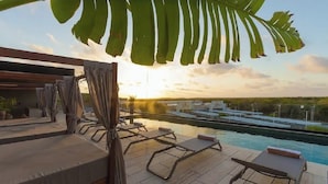 A rooftop pool area with lounge chairs and a view of the city skyline at sunset. - Brand new luxury studio condo,with private pool in Tuk  (Tulum)