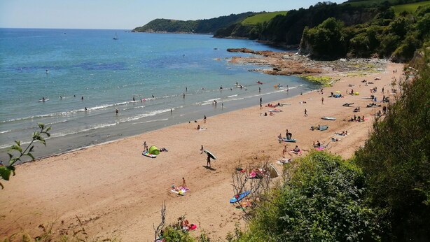 A beach with people, boats, and a rocky coastline. - Hillcroft (St Austell)