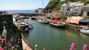 A harbor with boats docked, a stone wall, and a building with a sign that reads "Hotel House." - Hillcroft (St Austell)