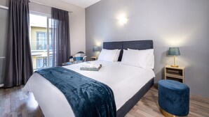 A modern hotel room with a large bed, two bedside tables, a small stool, and a view of the outside balcony. - RIVIERA HOTEL (Xylokastro-Evrostina)