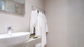 A bathroom with a large sink, a mirror, and a towel rack with multiple white towels. - RIVIERA HOTEL (Xylokastro-Evrostina)