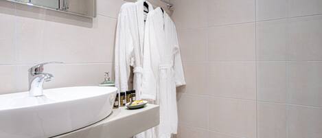 A bathroom with a large sink, a mirror, and a towel rack with multiple white towels.