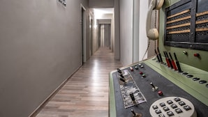 A hallway with a control panel on the right, featuring various buttons and a rotary dial. - RIVIERA HOTEL (Xylokastro-Evrostina)