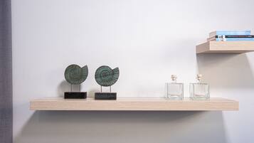 A wooden shelf with two decorative items and two glass bottles.