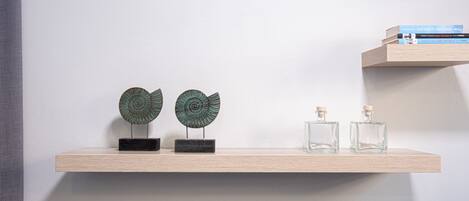 A wooden shelf with two decorative items and two glass bottles.
