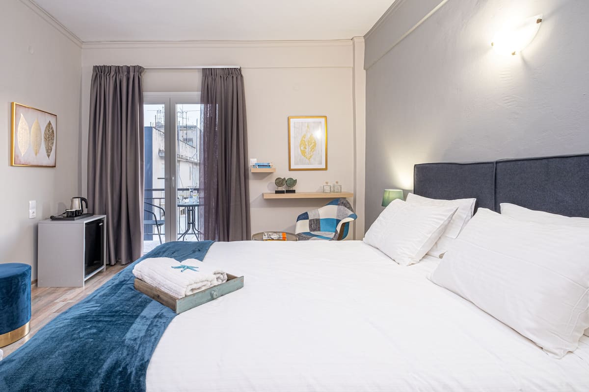 A hotel room with a large bed, a desk, a chair, and a view of the outdoors.