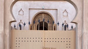 A large, beige wooden gate with a metal lock and decorative metal spikes. - Desert Villa Boutique Hotel Merzouga (Taouz)