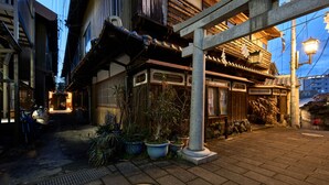 Un estrecho callejón con edificios tradicionales de madera, plantas en macetas y un farol de piedra.