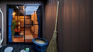 Una habitación japonesa tradicional con suelo de tatami, una puerta corredera azul y una escoba de bambú apoyada en la pared.