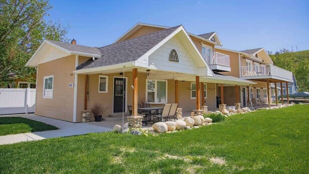 A two-story house with a covered porch, a stone retaining wall, and a well-maintained lawn.