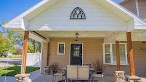 A covered porch with a stone column, a black door, and a window with a pointed arch.