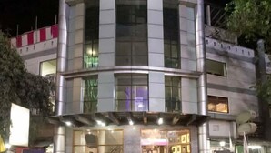 Un edificio de varios pisos con grandes ventanales y una entrada de esquina curva.