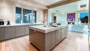 Una cucina moderna con una grande isola, elettrodomestici integrati e vista all'esterno.