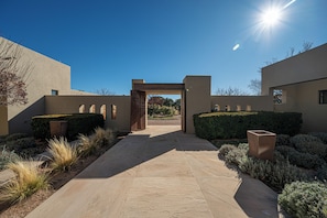 A modern building entrance with a clear pathway leading to a covered area, surrounded by well-maintained landscaping. - Private 10-Acre Estate & Mountain Views (Santa Fe)