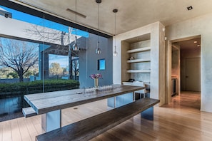 A modern kitchen with a wooden island, pendant lights, and a view of the outdoors. - Private 10-Acre Estate & Mountain Views (Santa Fe)