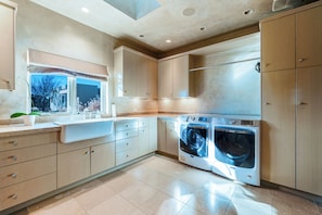 A modern kitchen with built-in appliances, including a washing machine and a sink with a window above. - Private 10-Acre Estate & Mountain Views (Santa Fe)