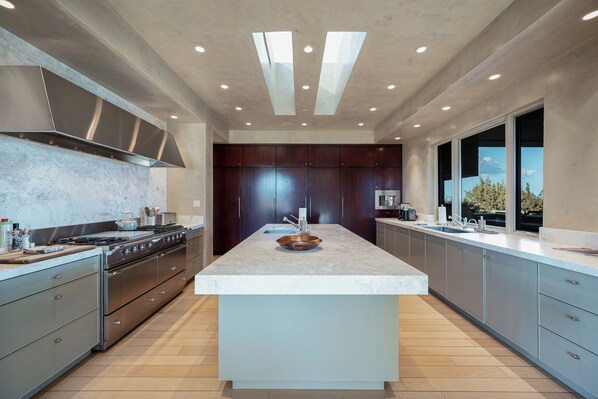 A modern kitchen with a central island, stainless steel appliances, and a large window providing natural light. - Private 10-Acre Estate & Mountain Views (Santa Fe)