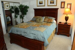 A bedroom with a wooden bed, a nightstand, a lamp, and two potted plants. - Seven Springs Sunridge 3 Bedroom Deluxe Condo with Loft by RedAwning (Champion)