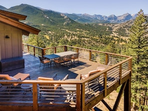 A wooden deck with outdoor furniture, overlooking a mountainous landscape.