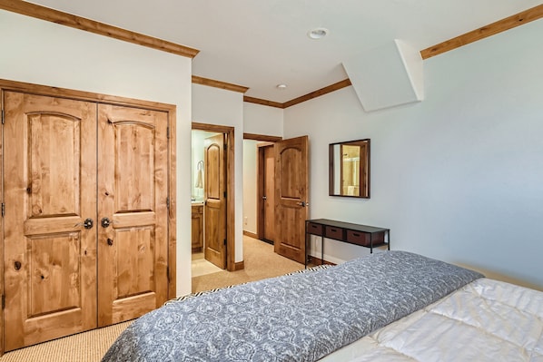 Ein Schlafzimmer mit einem Bett, einem Holzschrank und einem kleinen Schreibtisch mit Spiegel.