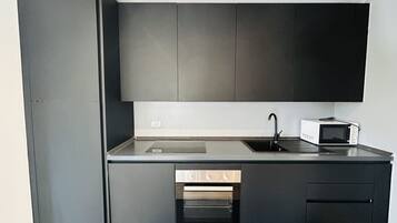 Een moderne keuken met donkere kastjes, een inbouwoven, een magnetron en een spoelbak.