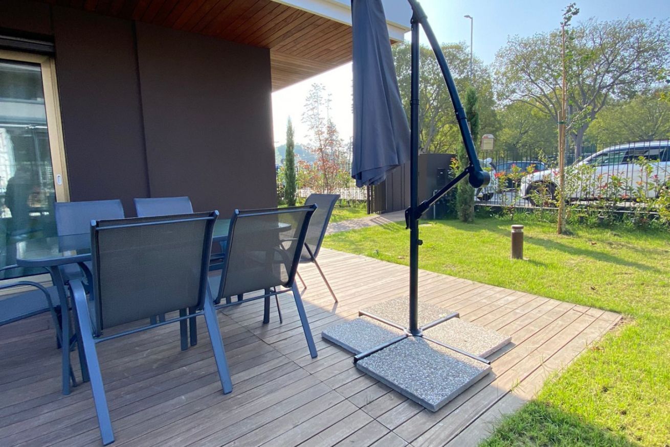 En uteplats med ett bord och stolar, ett trädäck och ett takförsett område med ett bord och stolar.