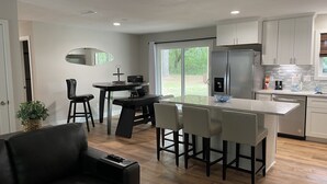 A modern kitchen with a central island, stainless steel appliances, and a dining area with a black table and chairs. - (Sleeps 7) 3 bedroom/2 bath BRING YOUR BOAT/WAVERUNNERS-Lots of Parking Space (Freeport)