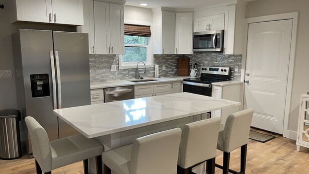 A modern kitchen with white cabinetry, stainless steel appliances, a central island with bar stools, and a window with a view. - (Sleeps 7) 3 bedroom/2 bath BRING YOUR BOAT/WAVERUNNERS-Lots of Parking Space (Freeport)