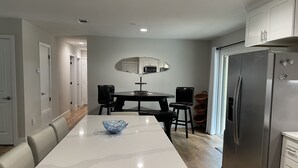 A modern kitchen with a white countertop, black chairs, a stainless steel refrigerator, and a dining table with a blue bowl. - (Sleeps 7) 3 bedroom/2 bath BRING YOUR BOAT/WAVERUNNERS-Lots of Parking Space (Freeport)
