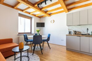 A modern kitchen with wooden beams, a dining area with a round table and chairs, and a sofa.