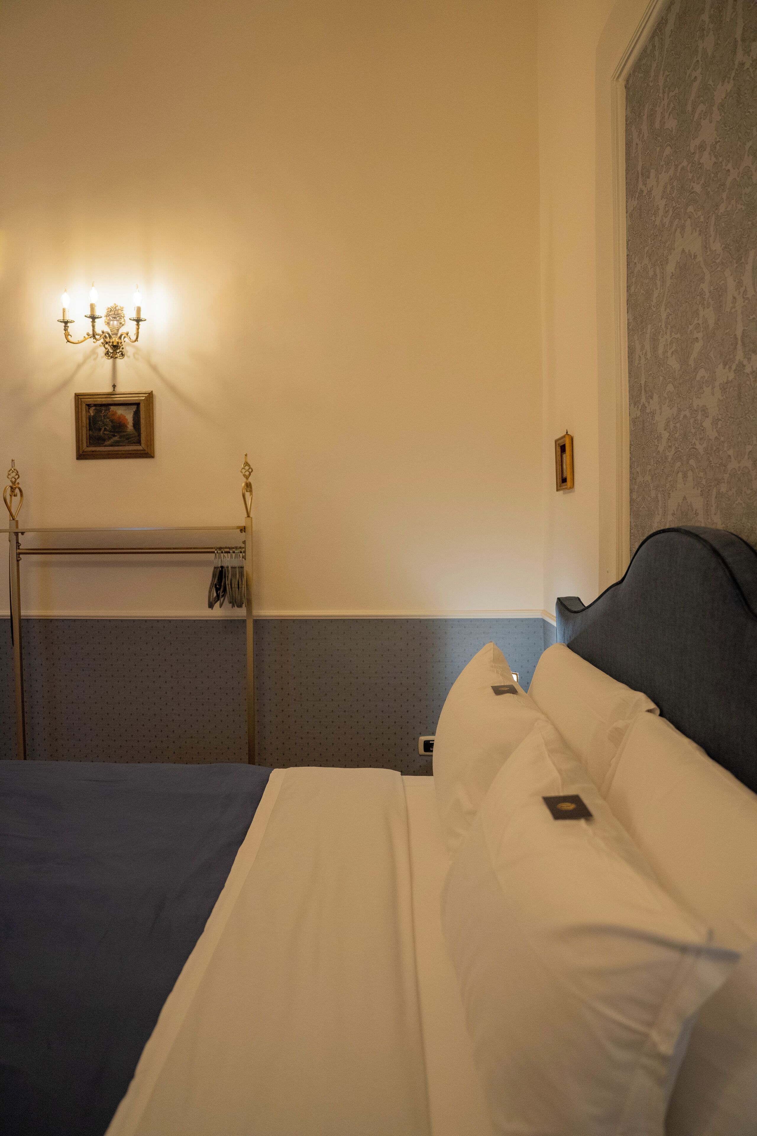 A hotel room with a bed, a bedside table, a lamp, and a wall-mounted picture.