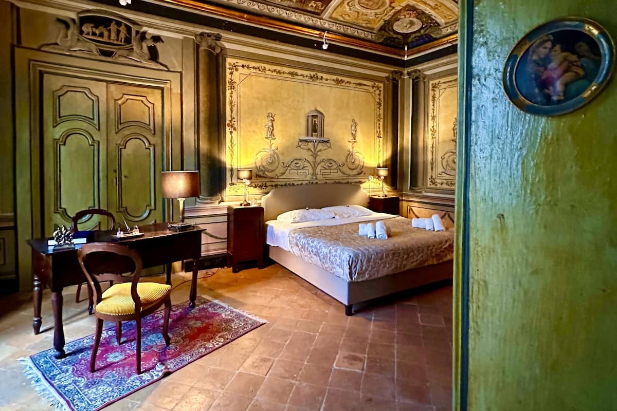 Ein Schlafzimmer mit einem Bett, einem Schreibtisch, einem Stuhl und einer grünen Wand.