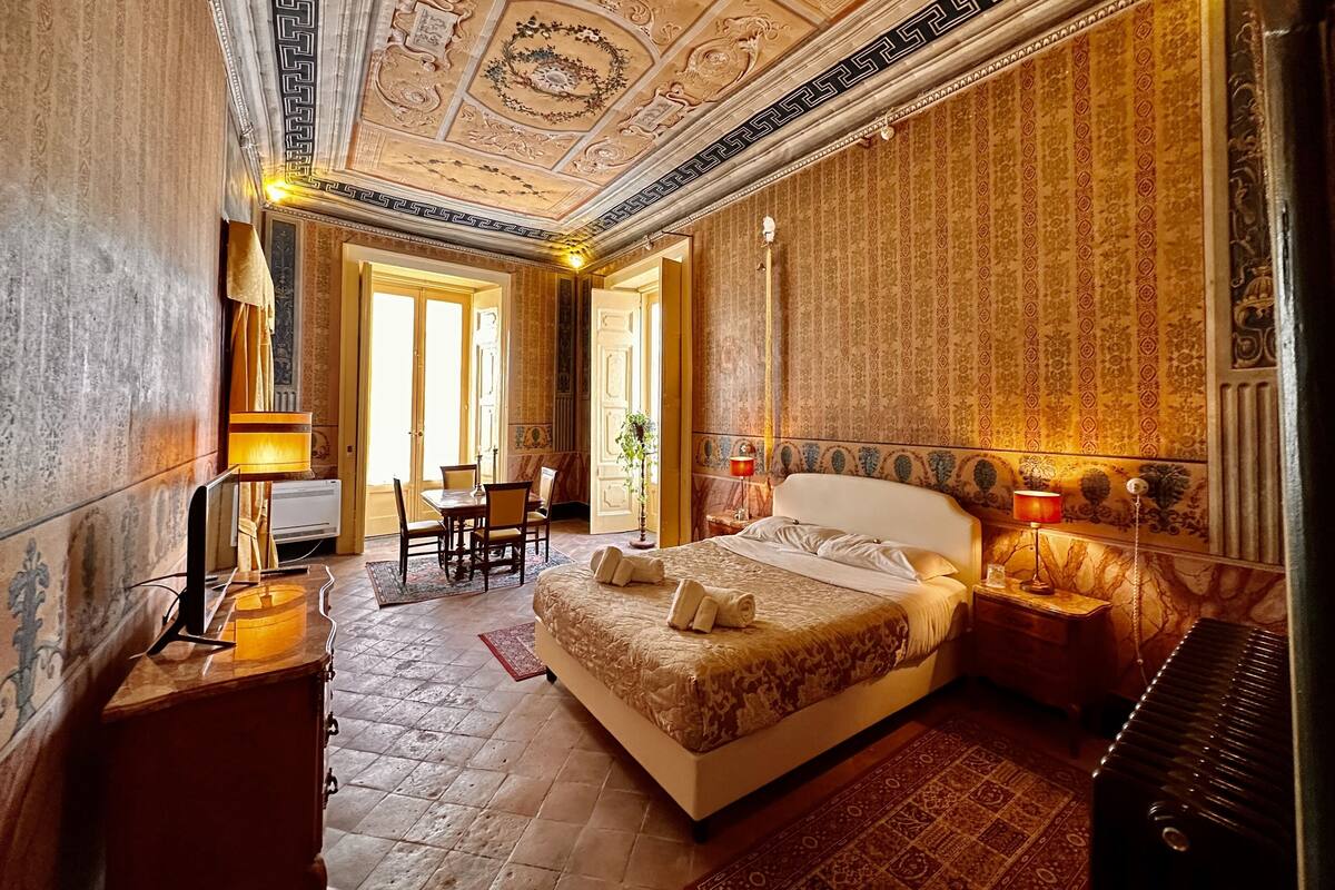 Ein Hotelzimmer mit einem großen Bett, einem Schreibtisch, einem Sessel und einem Klavier.